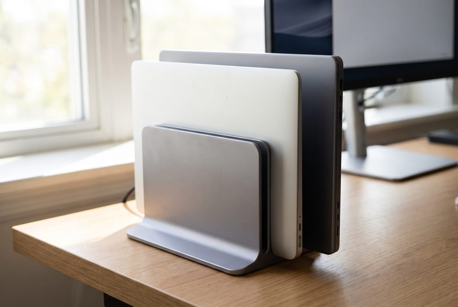 UGREEN gray dual-slot aluminum vertical stand holding two closed laptops upright side by side on a desk